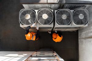 Top view of two workers on commercial HVAC system
